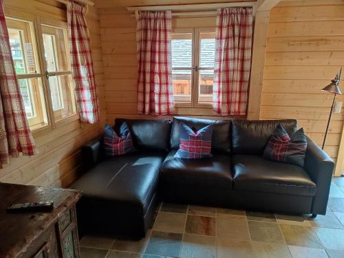 a leather couch in a living room with windows at Schlosswirt Chalets & Apartments in Großkirchheim