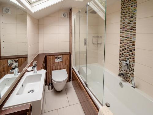 a bathroom with a toilet and a sink and a shower at Wayside Cottage 1637 in Millom