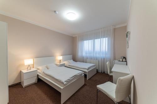 a hotel room with two beds and a chair at Penzion Lomská Vyhlídka in Lom u Mostu