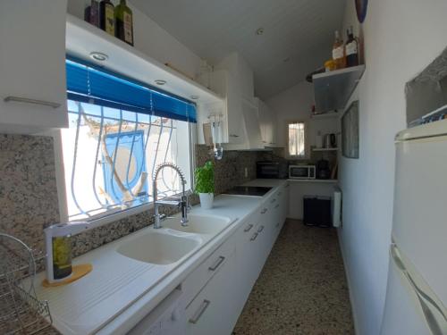 eine weiße Küche mit einem Waschbecken und einem Fenster in der Unterkunft Maison de pecheur in Sigean
