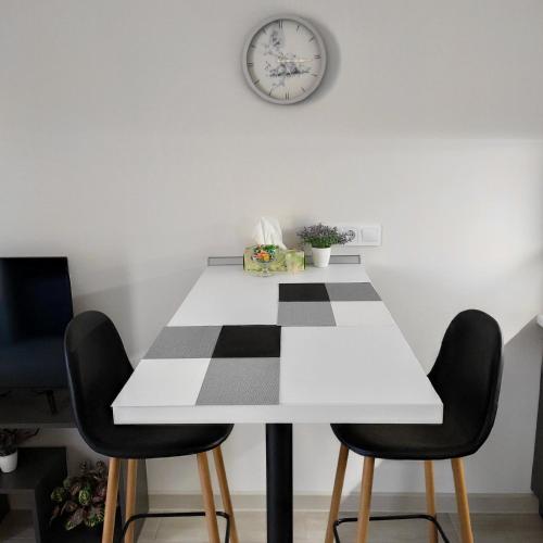 a white table with two chairs and a clock on the wall at Небольшая уютная квартира вблизи Лузановки в Одессе in Korsuntsy
