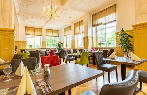 a restaurant with tables and chairs and windows at Hotel Badehof in Bad Salzschlirf