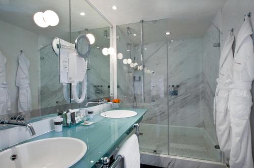 un bagno con due lavandini e una doccia in vetro di Hôtel Le Saint-James a Bouliac