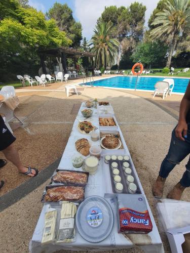 a long table with food on it next to a pool at aldea אלדאה in Nir‘am