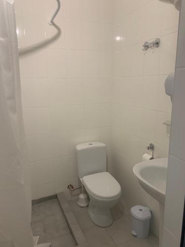 a white bathroom with a toilet and a sink at ZIG ZAG in Kamianets-Podilskyi