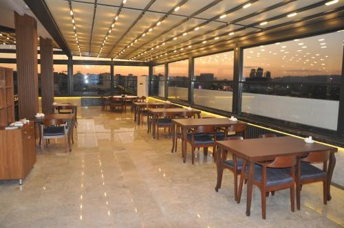 - un restaurant avec des tables, des chaises et de grandes fenêtres dans l'établissement GOLAZ SUİT OTEL, à Ankara