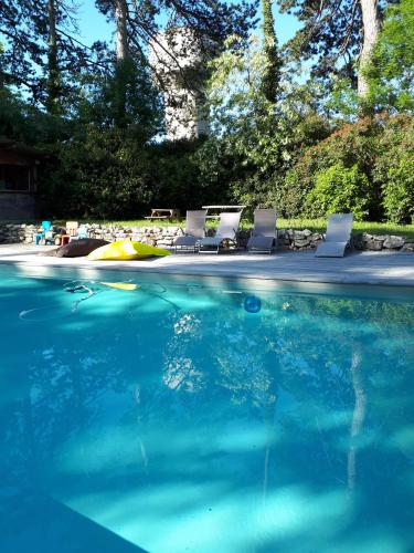 a swimming pool with chairs and blue water at Le Jardin Des Cèdres in Lavaur