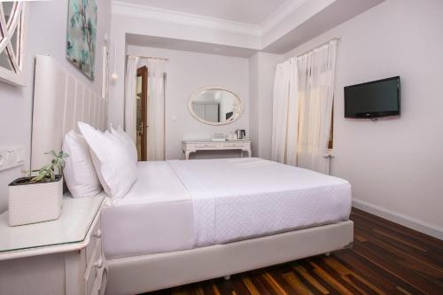a white bedroom with a white bed and a television at Ascot Hotel Büyükada in Buyukada