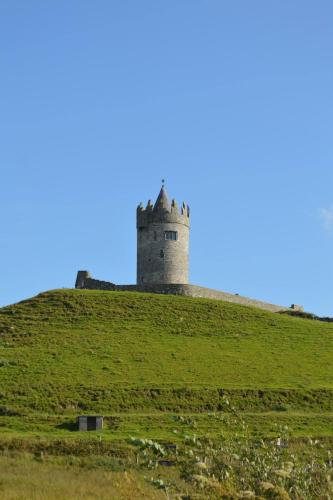 a castle on top of a grassy hill at Doolin Lanelodge -Room Only- in Doolin
