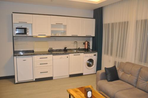 a kitchen with white cabinets and a couch in a living room at GOLAZ SUİT OTEL in Ankara