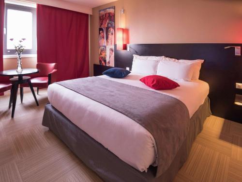 a hotel room with a large bed with red curtains at Hotel Mercure Alger Aéroport in Dar el Beïda