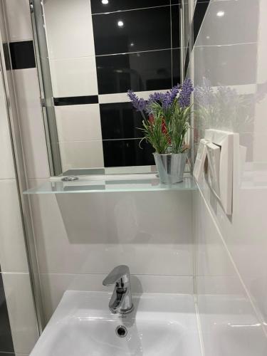 lavabo con espejo y jarrón de flores en Noclegi u Marii - Koninki, en Poręba Wielka