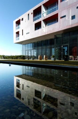 a building with its reflection in a body of water at LOISIUM Wine & Spa Hotel Langenlois in Langenlois
