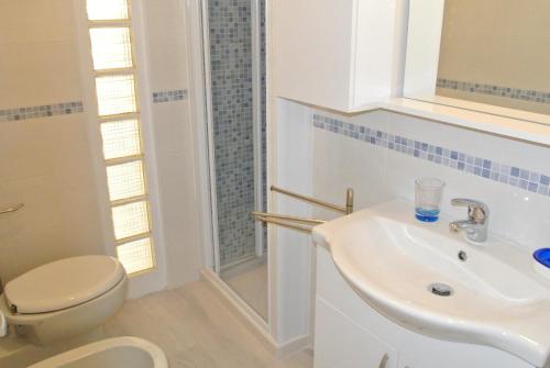 een witte badkamer met een toilet en een wastafel bij DUNA 4 in Lignano Sabbiadoro