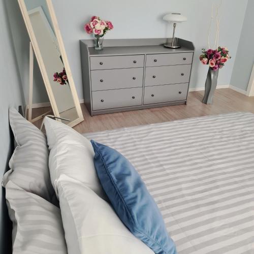 a bedroom with a white bed with a blue pillow at Alejas Lux Apartment in Liepāja