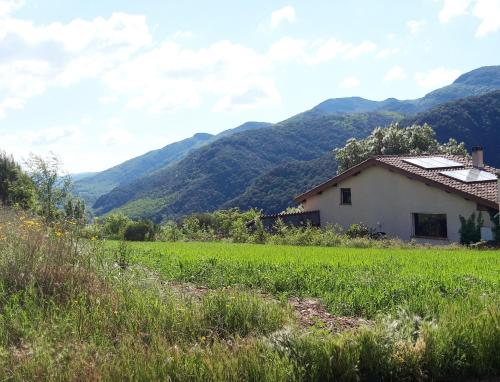 une maison dans un champ avec des montagnes en arrière-plan dans l'établissement Maison du Caroux, with a pool with an amazing view, à Saint-Martin-de-lʼArçon
