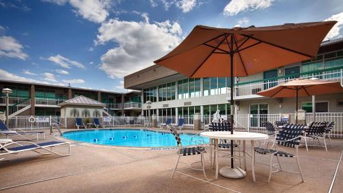 einen Pool mit einem Tisch, Stühlen und einem Sonnenschirm in der Unterkunft SureStay Plus Hotel by Best Western Brandywine Valley in Wilmington