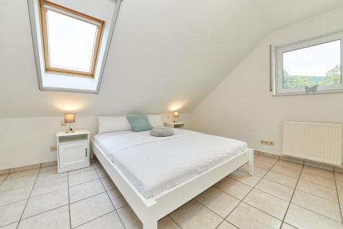 ein weißes Schlafzimmer mit einem Bett und zwei Fenstern in der Unterkunft Moselschleife in Bernkastel-Kues