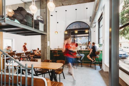 a woman running through a restaurant with tables and chairs at Athens Backpackers in Athens