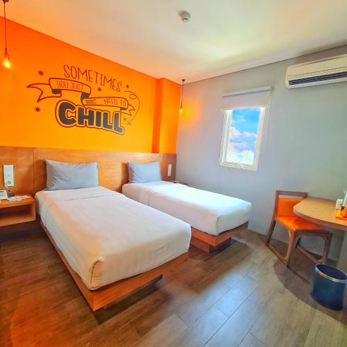 two beds in a room with an orange wall at Radja Art and Boutique Hotel Simpang Lima in Semarang