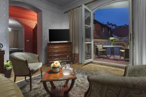 a living room with a television and a balcony at Boutique Hotel Constans in Prague