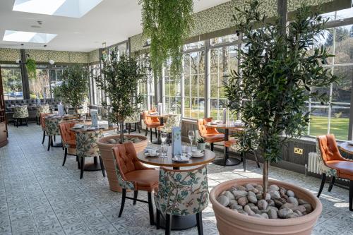 a restaurant with tables and chairs and potted trees at Dunkeld House Hotel in Dunkeld