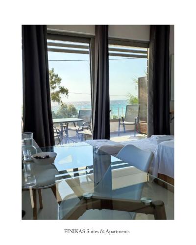 a room with a glass table and a view of the ocean at Finikas Suites & Apartments Airport By Airstay in Artemida