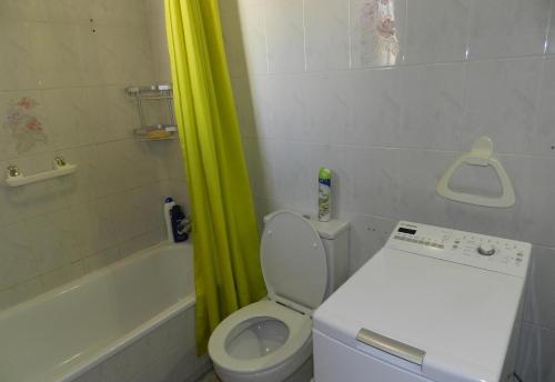 e bagno con servizi igienici e vasca con tenda gialla per la doccia. di Playa flamenca a Playa Flamenca
