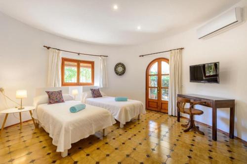 a bedroom with two beds and a table and a piano at Villa Rosa in Sant Josep de sa Talaia