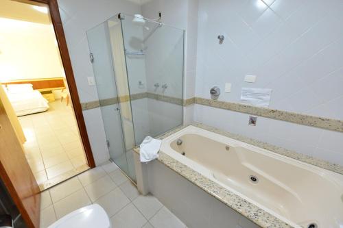 a bathroom with a tub and a shower and a toilet at Vind's Plaza Hotel in Caratinga
