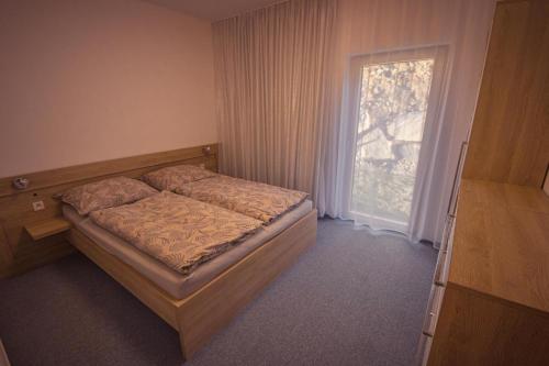 a small bedroom with a bed and a window at ZORE JASNÁ Apartments in Demanovska Dolina