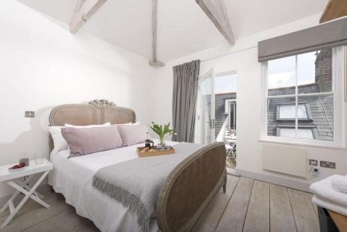 ein weißes Schlafzimmer mit einem großen Bett und einem Fenster in der Unterkunft Upper Chandlers Cottage in Mousehole