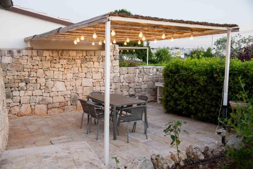 a patio with a table and chairs under a wooden pergola at Trulli Paparale in Alberobello