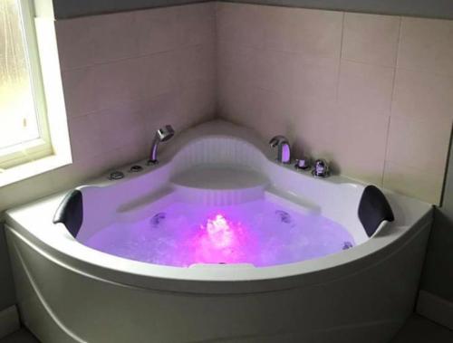 a bath tub with a pink light in it at Inviting 2-Bed Bungalow in Heacham with spa bath in Heacham