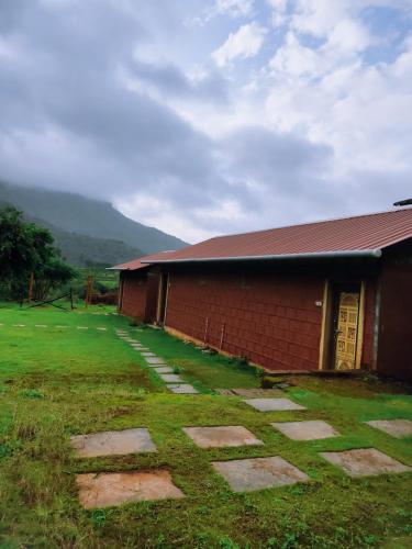 a red brick building with a grass yard next to it at Mysticstays Resort in Wai