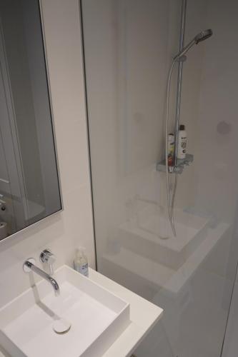 a white bathroom with a sink and a shower at Nieuwpoortnachten res. Rubens in Nieuwpoort
