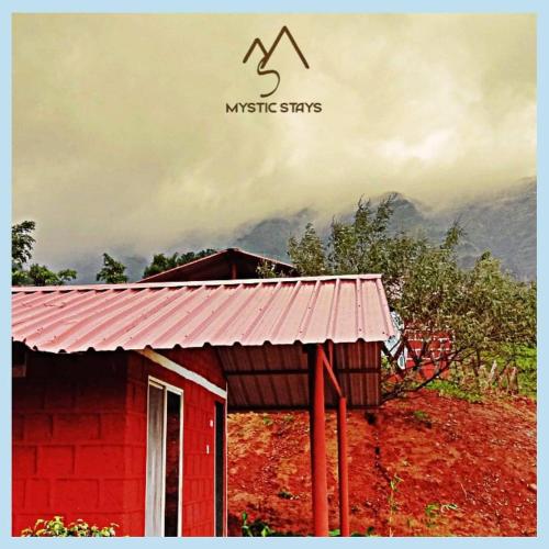a red building with a mountain in the background at Mysticstays Resort in Wai