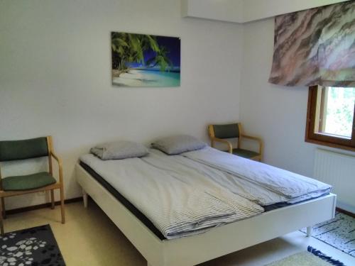 a bedroom with a bed and two chairs in it at Särkisalo 5 in Konnevesi
