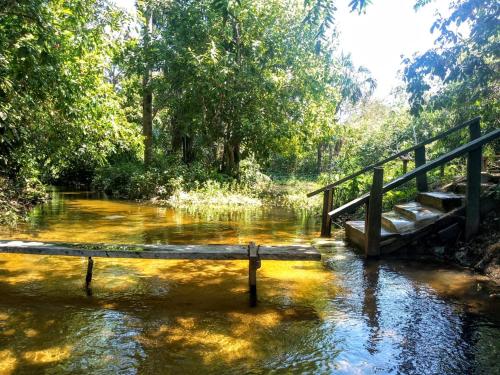 a wooden bridge over a river with trees and water at RECANTO DO SABIÁ in Carolina