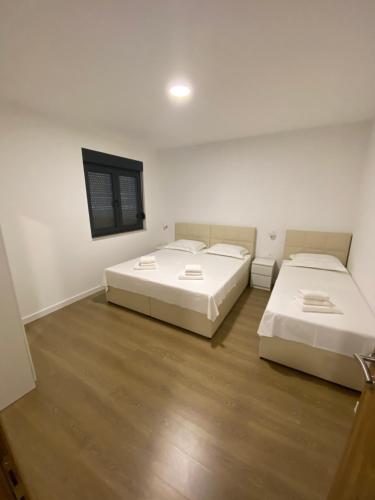 two beds in a room with white walls and wooden floors at Villa ELENA in Međugorje
