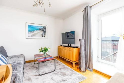 a living room with a couch and a tv and a window at Fresh, modern West End apartment beside Hydro in Glasgow