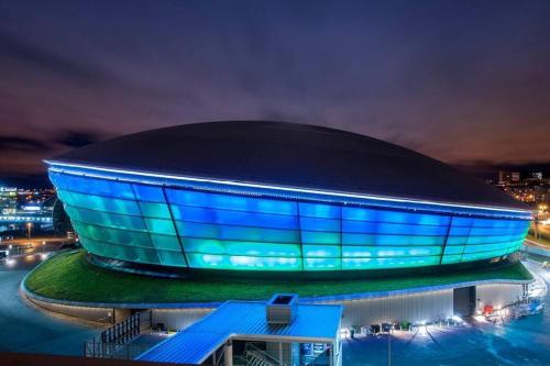 a building with blue lights on it at night at Fresh, modern West End apartment beside Hydro in Glasgow