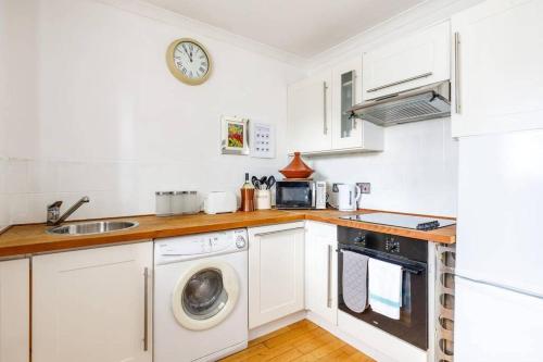 a kitchen with white cabinets and a washer and dryer at Fresh, modern West End apartment beside Hydro in Glasgow