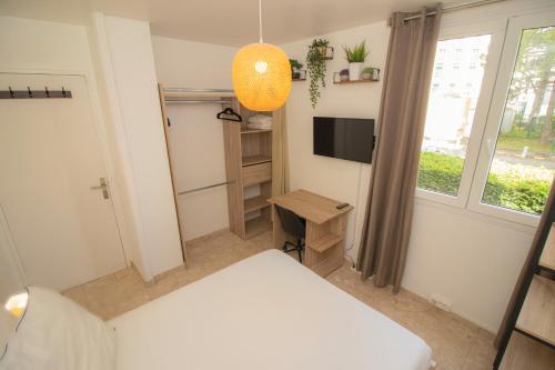 a bedroom with a bed and a desk and a television at La Garden Room Logement en Colocation in Le Plessis-Robinson
