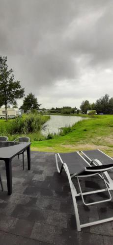 a picnic table and chairs next to a lake at Resort Land & Zee in Scharendijke