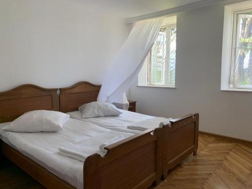 a bedroom with a bed with white sheets and two windows at House 122 in K'obulet'i