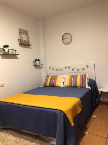 1 dormitorio con 1 cama y reloj en la pared en Ático Mirador de Peregrinos, en Granada