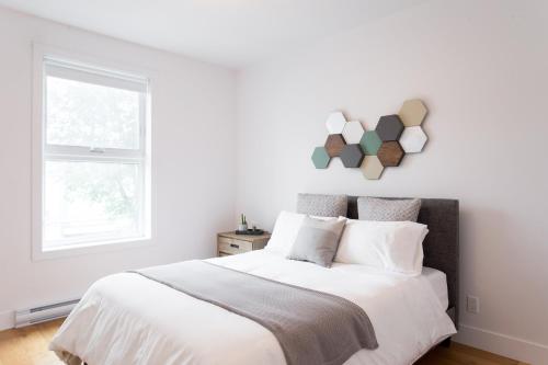 a white bedroom with a bed and a window at Hip, Stylish Apartment in Little Italy by Den Stays A in Montréal
