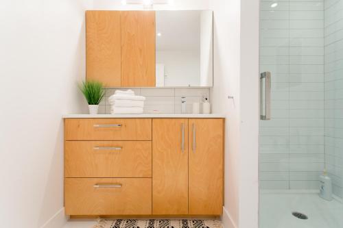 a bathroom with a wooden cabinet and a shower at Hip, Stylish Apartment in Little Italy by Den Stays A in Montréal