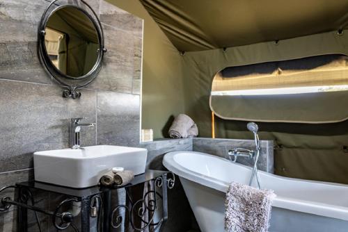 bagno con lavandino, vasca e specchio di Hartenbos Private Game Lodge a Hartenbos